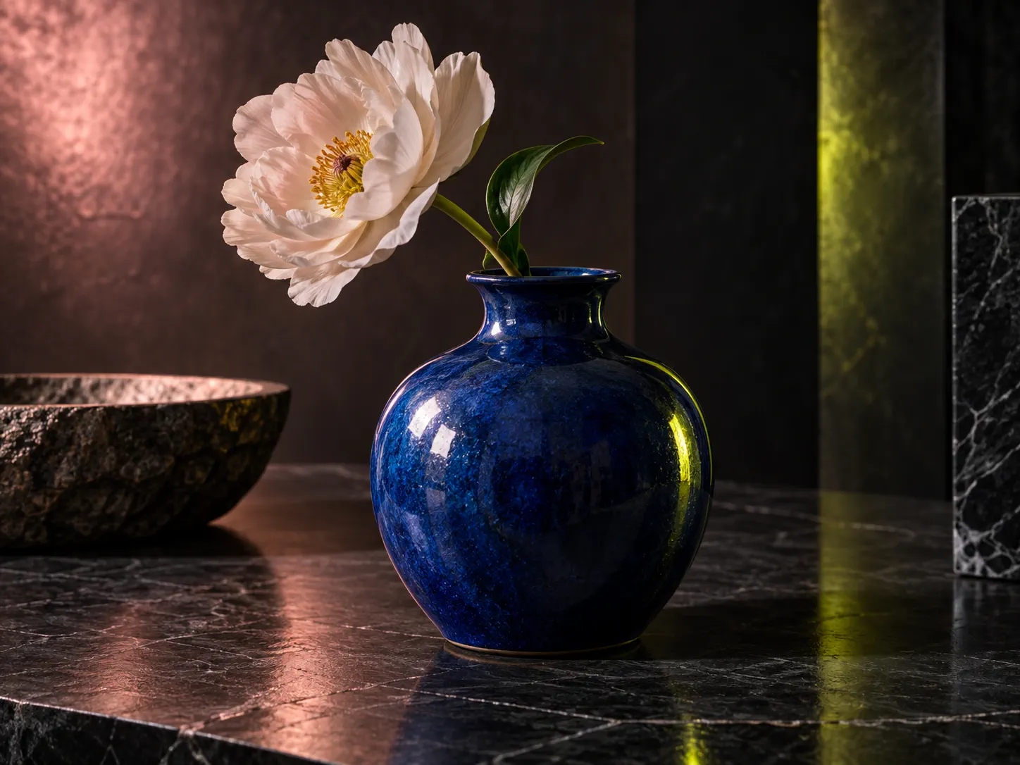 Vase en céramique bleue avec une fleur blanche sur une table en pierre